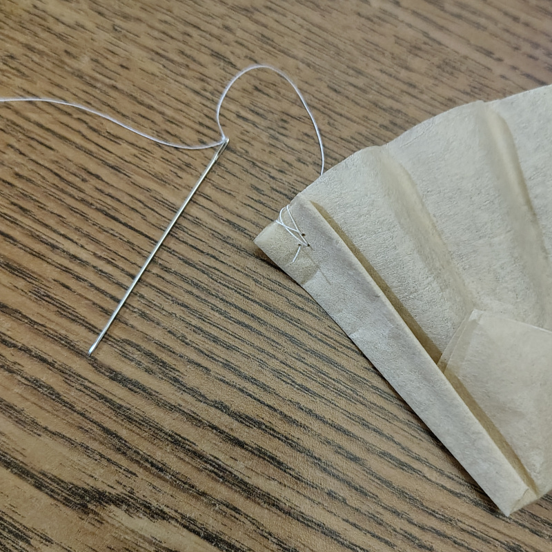 A coffee filter cup secured with cotton thread